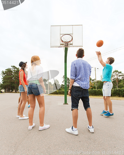 Image of group of happy teenagers playing basketball