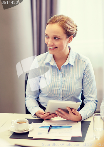 Image of smiling woman holding tablet pc computer in office