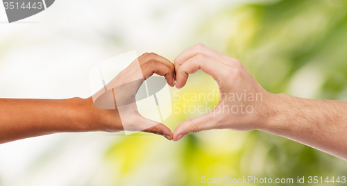 Image of woman and man hands showing heart shape