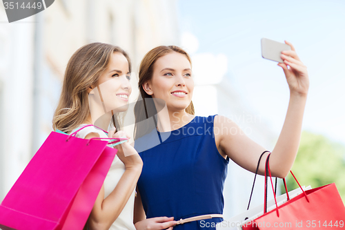 Image of happy women with shopping bags and smartphone