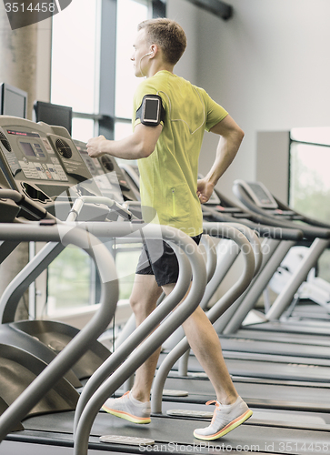 Image of man with smartphone exercising on treadmill in gym