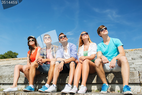 Image of group of smiling friends sitting on city street