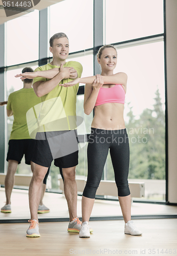 Image of smiling man and woman exercising in gym