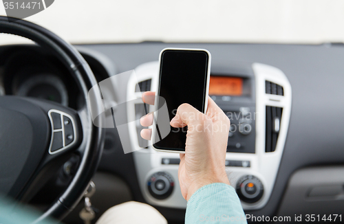 Image of close up of man hand with smartphone driving car