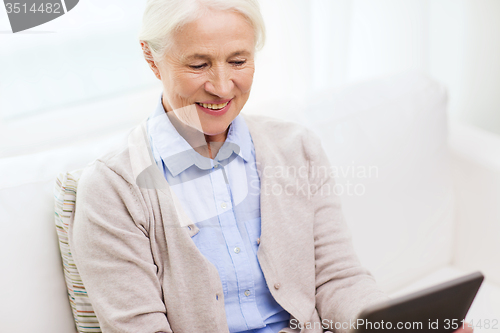 Image of happy senior woman with tablet pc at home