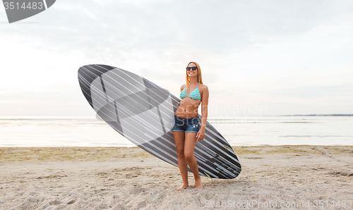 Image of smiling young woman with surfboard on beach