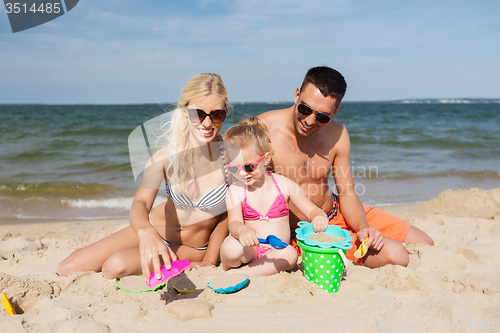 Image of happy family playing with sand toys on beach