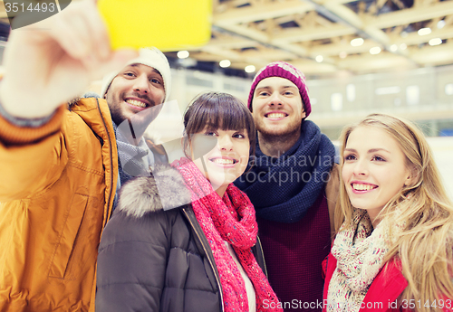 Image of happy friends with smartphone on skating rink
