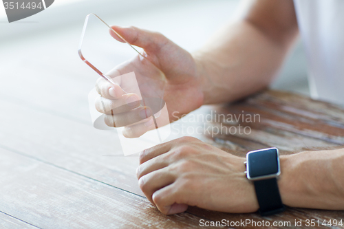 Image of close up of hands with smart phone and watch
