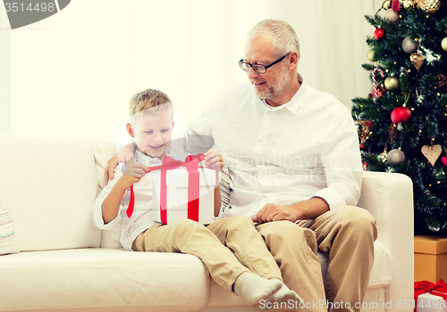 Image of smiling grandfather and grandson with gift box