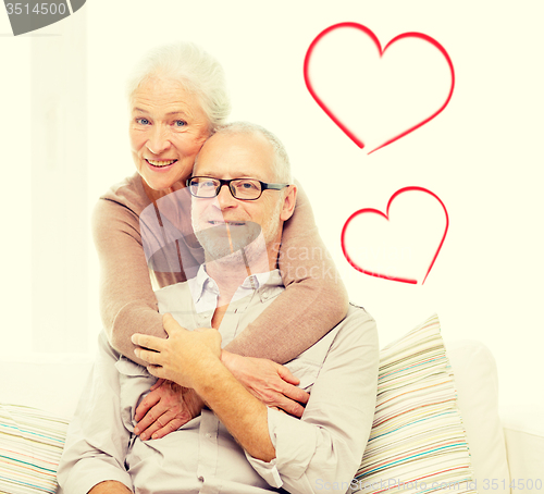 Image of happy senior couple hugging on sofa at home