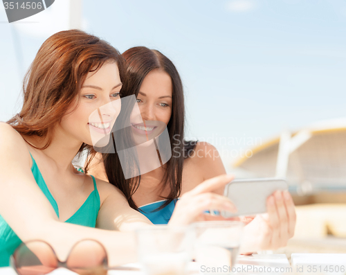 Image of girls looking at smartphone in cafe on the beach