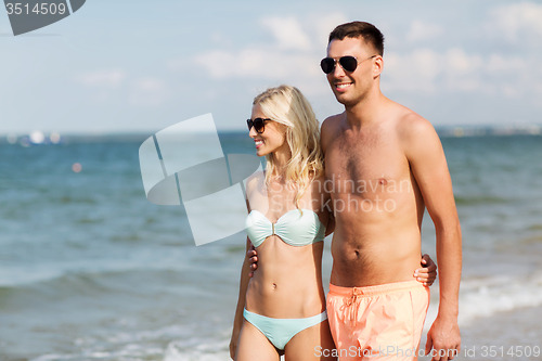 Image of happy couple in swimwear walking on summer beach