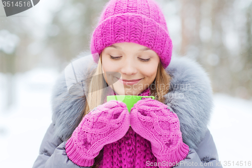 Image of smiling young woman with cup in winter forest