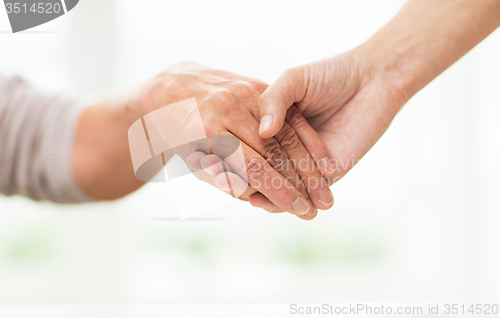 Image of close up of senior and young woman holding hands