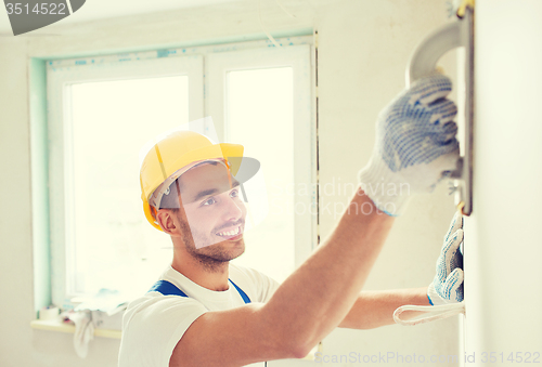 Image of smiling builder working with grinding tool indoors