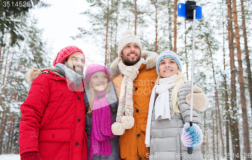 Image of smiling friends with smartphone in winter forest