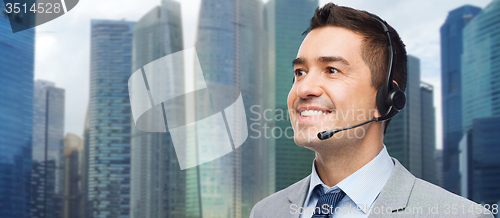 Image of happy businessman in headset over city background