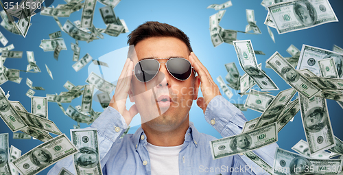 Image of surprised man under dollar money rain