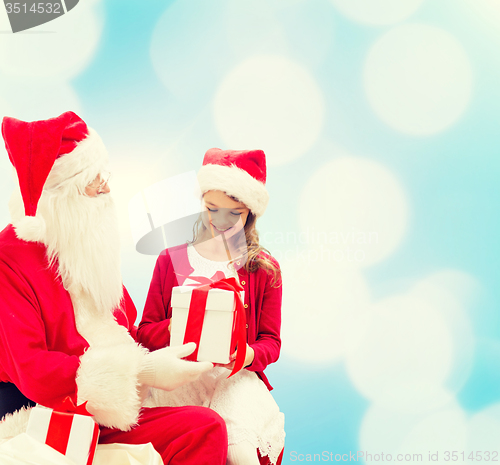 Image of smiling little girl with santa claus and gifts