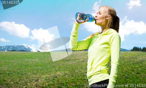 Image of woman drinking water after doing sports outdoors