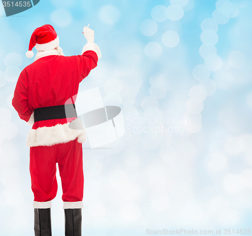 Image of man in costume of santa claus writing something