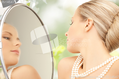 Image of beautiful woman with pearl necklace and mirror