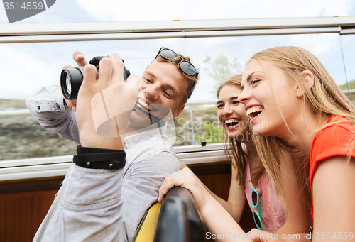 Image of happy friends with camera traveling by tour bus