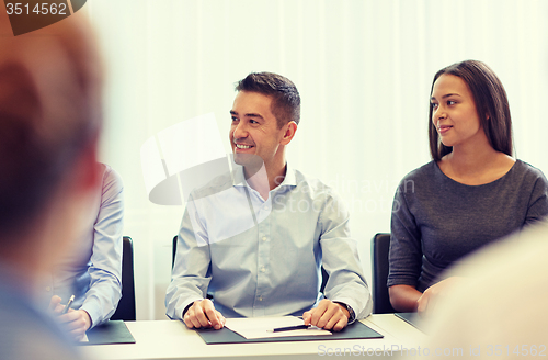 Image of group of smiling businesspeople meeting in office