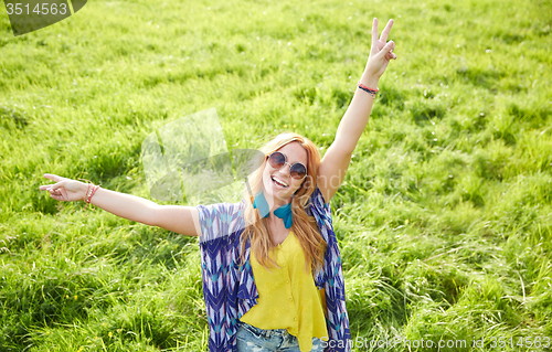 Image of smiling young hippie woman dancing on green field