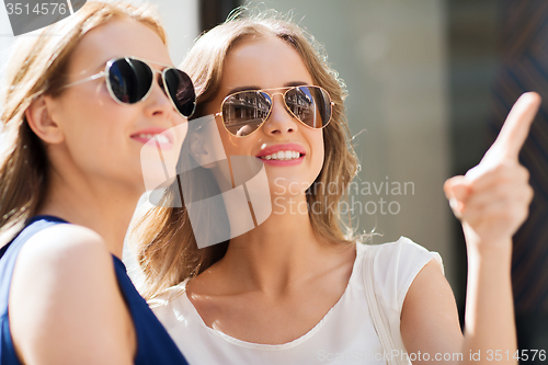 Image of happy women in sunglasses pointing finger outdoors