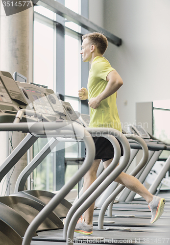 Image of smiling man exercising on treadmill in gym