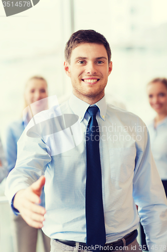 Image of smiling businessman making handshake in office