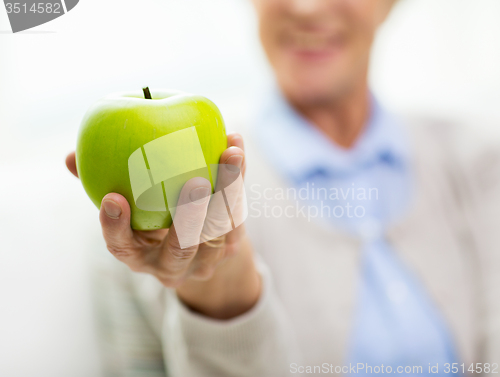 Image of close up of senior woman hand holding green apple