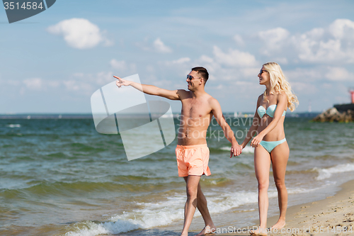Image of happy couple in swimwear walking on summer beach