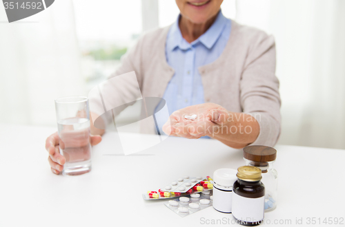 Image of happy senior woman with water and pills at home