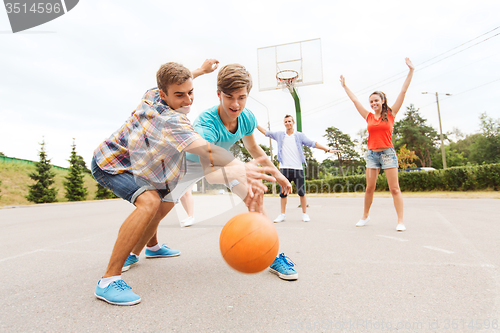 Image of group of happy teenagers playing basketball