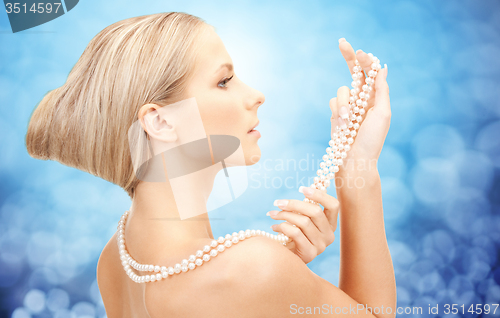 Image of beautiful woman with sea pearl necklace over blue