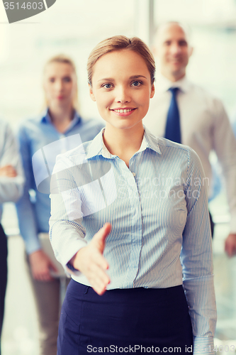 Image of smiling businesswoman making handshake in office