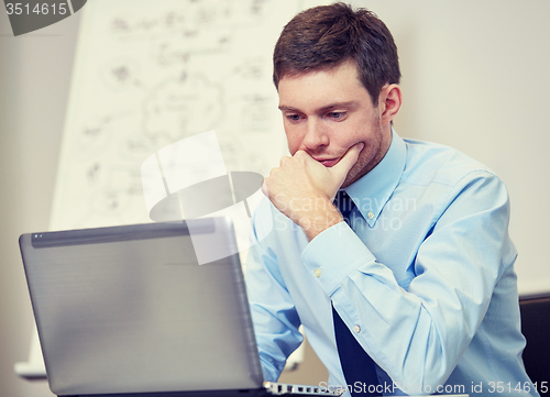 Image of businessman sitting with laptop in office