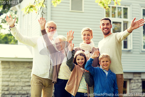 Image of happy family waving hands in front of house