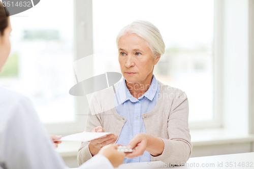 Image of doctor giving prescription and drug to woman 