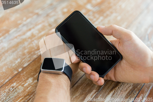 Image of close up of hands with smart phone and watch