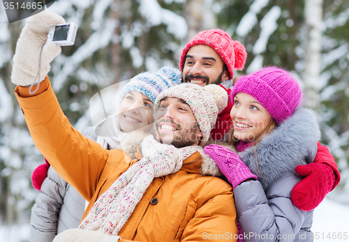 Image of smiling friends with camera in winter forest