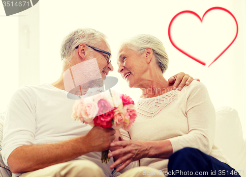 Image of happy senior couple with bunch of flowers at home