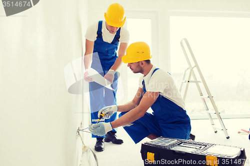 Image of builders with tablet pc and equipment indoors