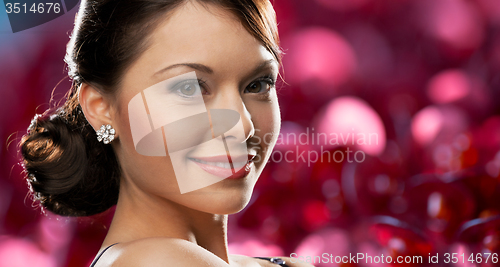 Image of happy woman with diamond earring over red lights