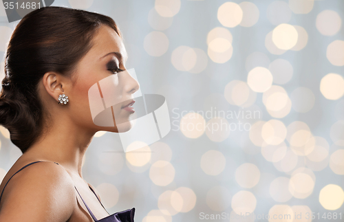 Image of woman with diamond earring over holidays lights