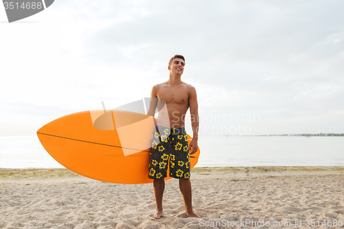 Image of smiling young man with surfboard on beach