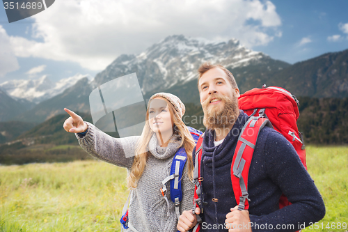 Image of happy couple with backpacks hiking over mountains